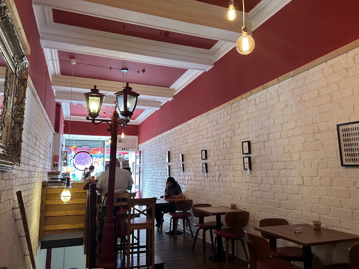 The long room: raspberry-red ceiling, whitewashed brick, a gilt mirror and a red Victorian lamppost inside.