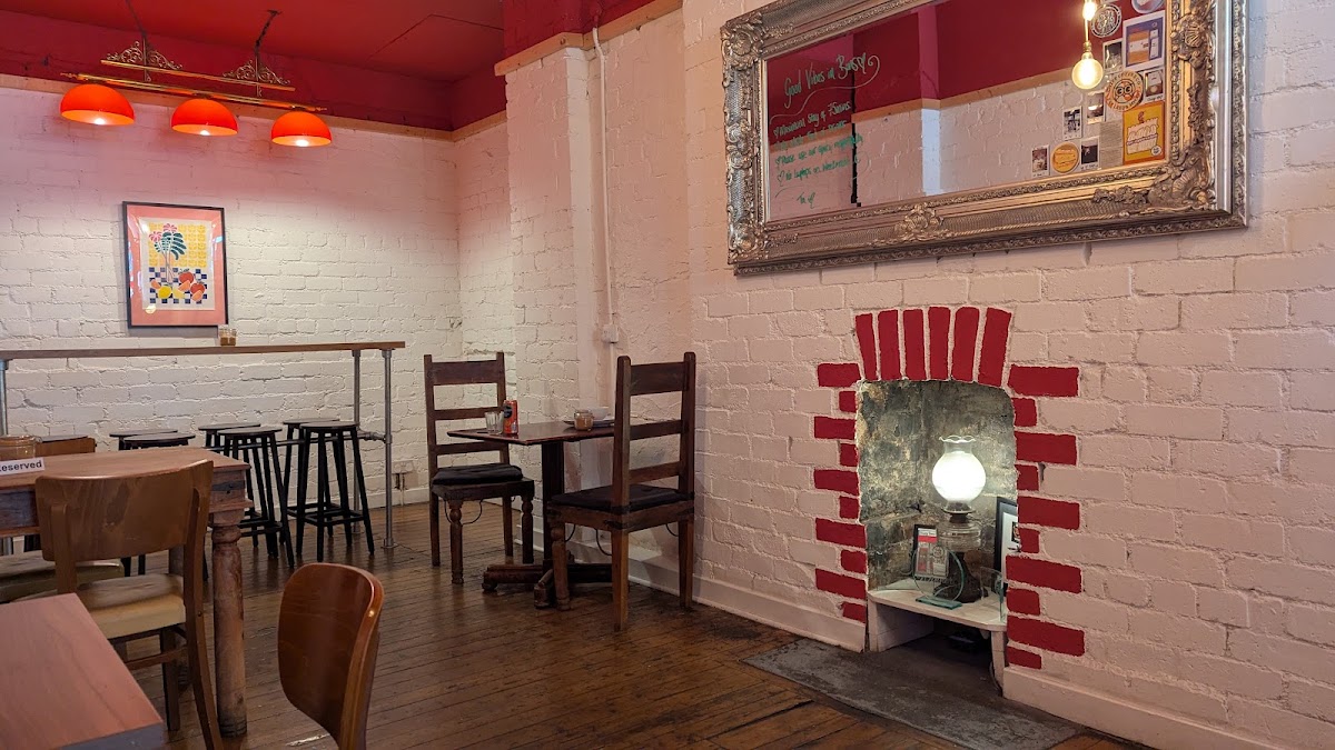 The back room: red pendant lamps, a fireplace picked out in red brick with an oil lamp, and a gilt mirror with writing on it.